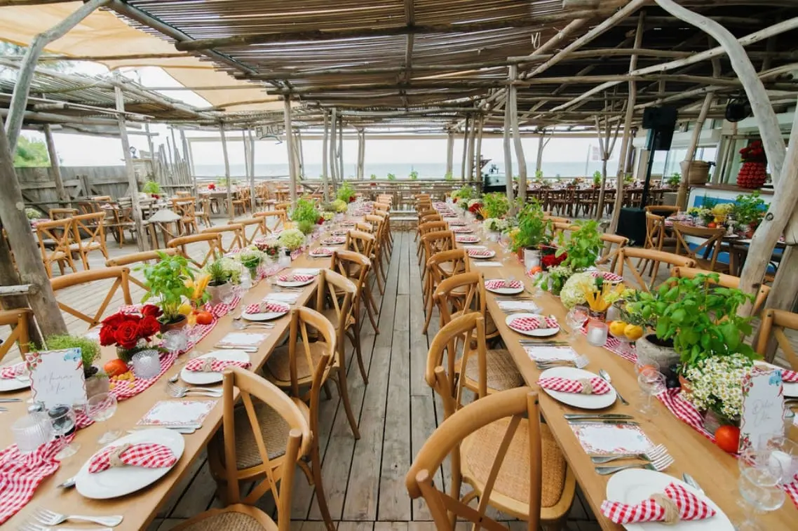 Longues tables aux nappes vichy rouges sous une pergola