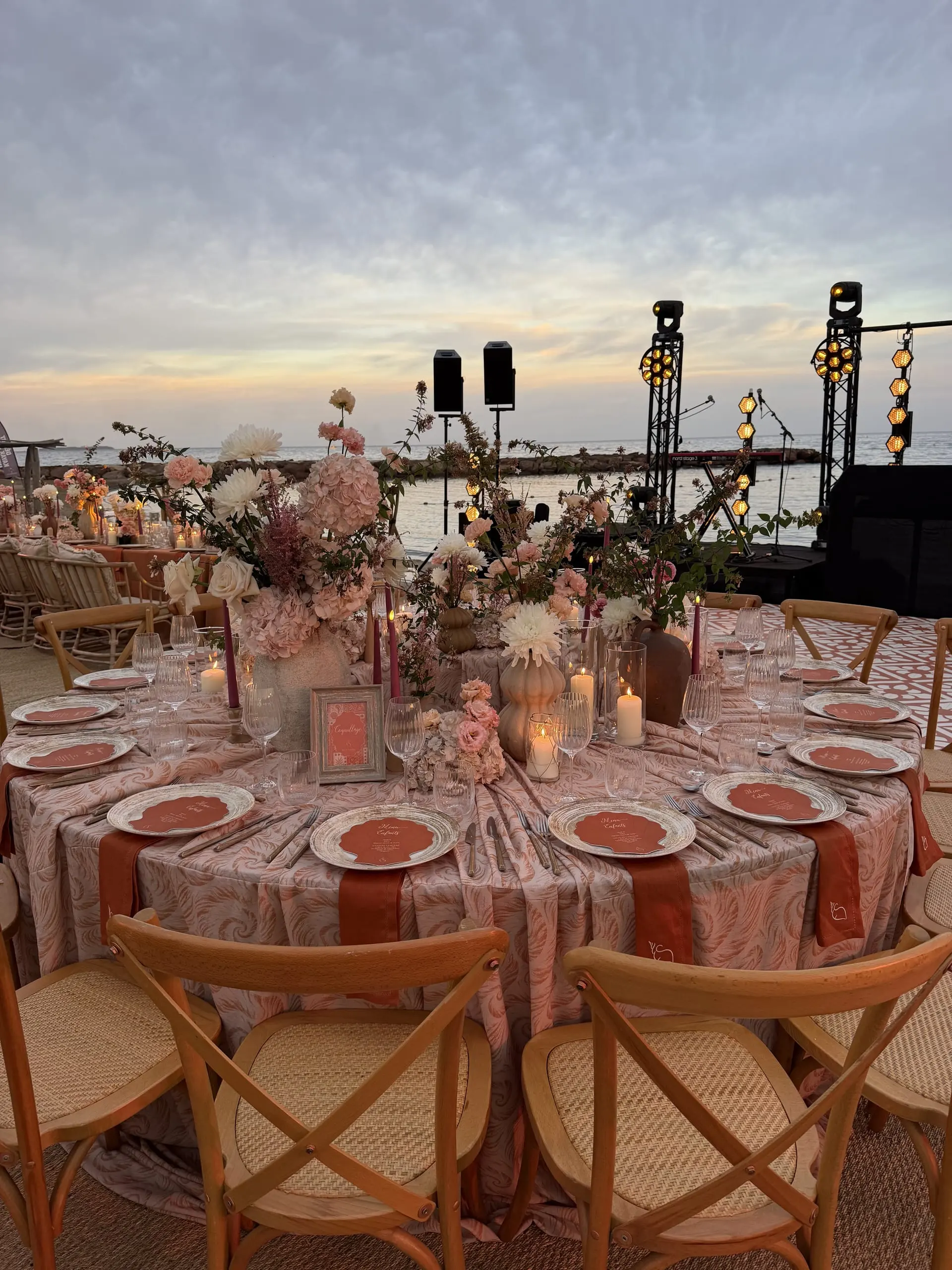 Tables rondes aux tons terracotta face à la mer au coucher du soleil