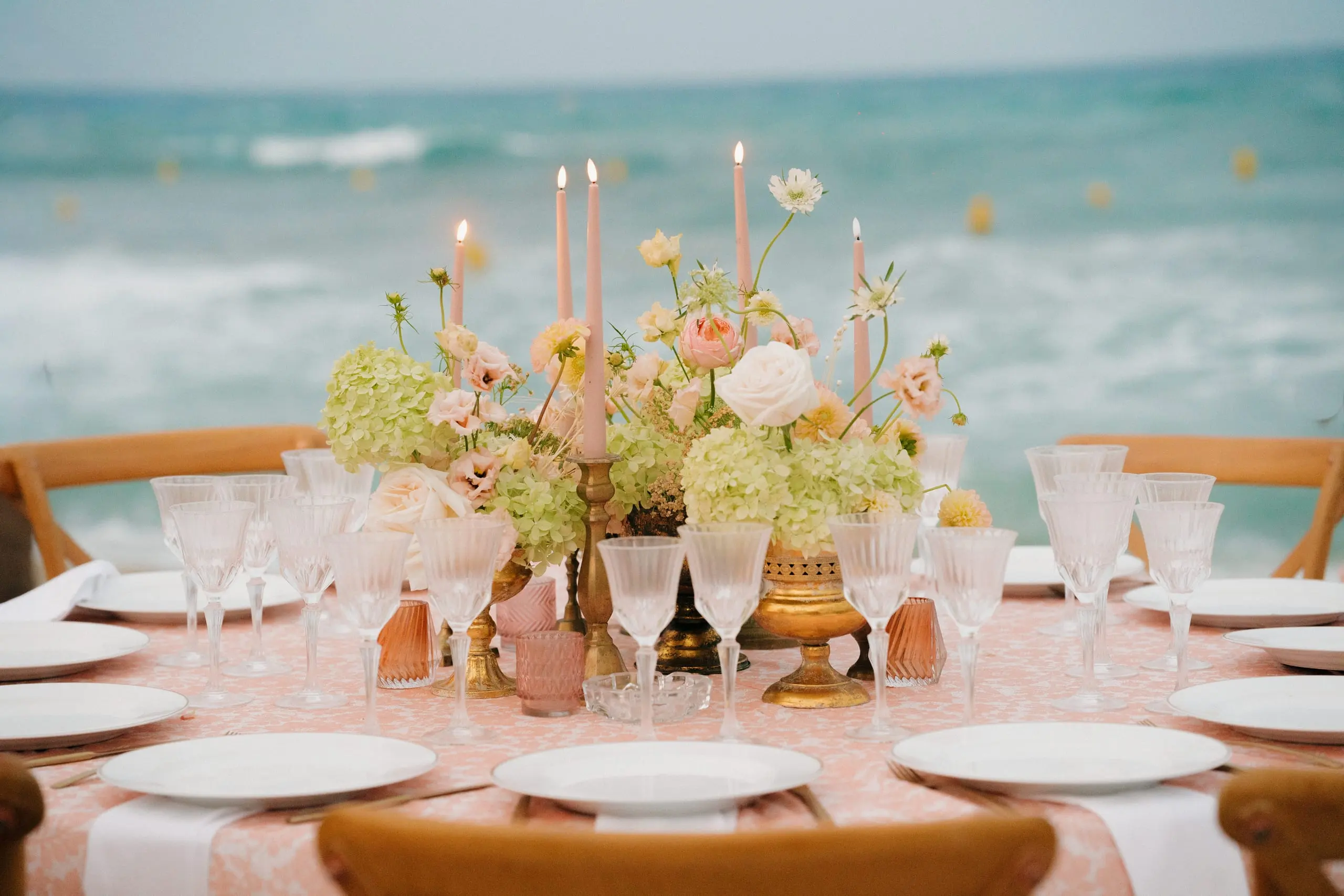 Table dressée face à la mer, bouquets aux tons poudrés